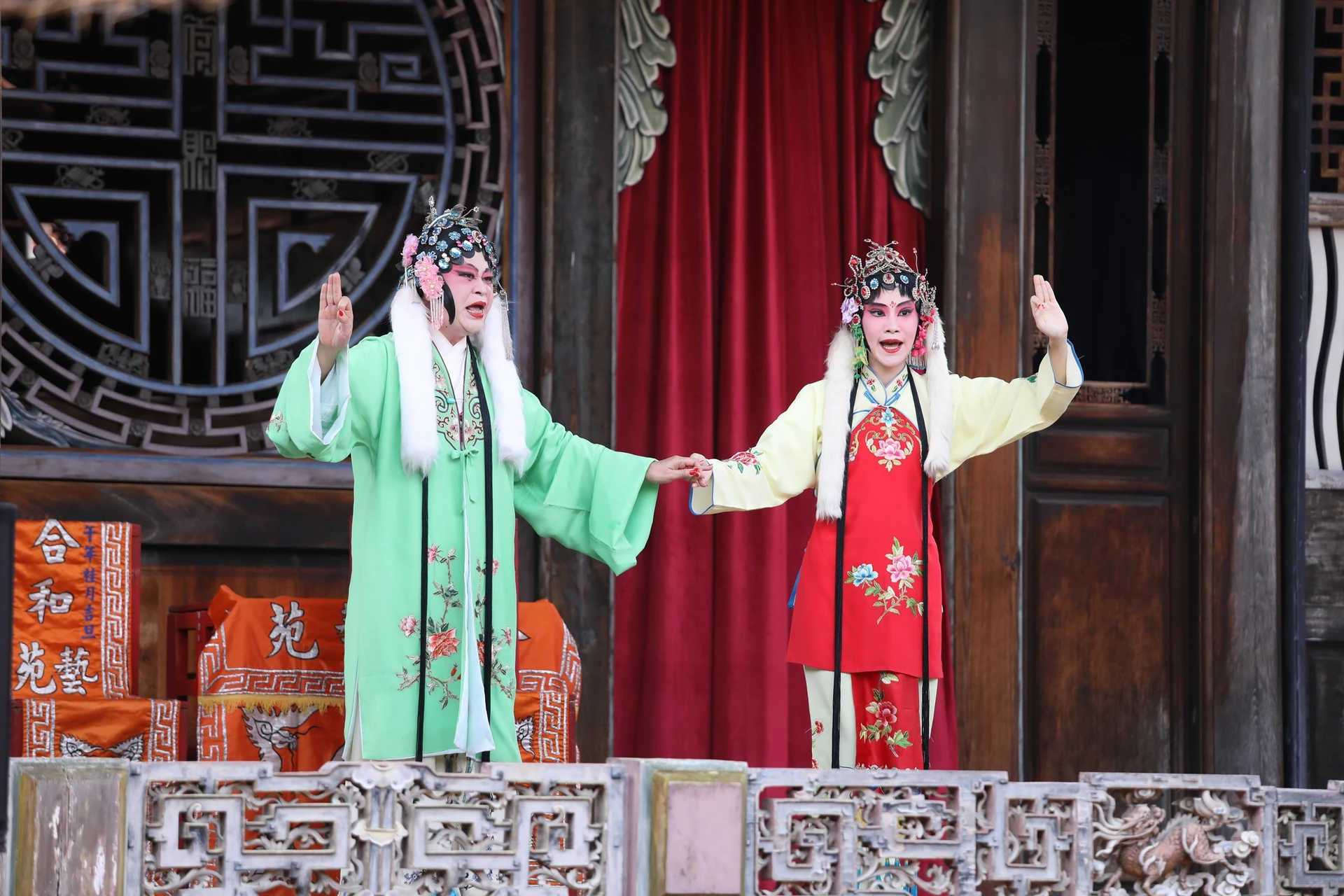 兩名身穿傳統戲曲服飾的演員在舞台上表演南管戲曲，一人著綠衣、一人著紅衣，姿態生動。